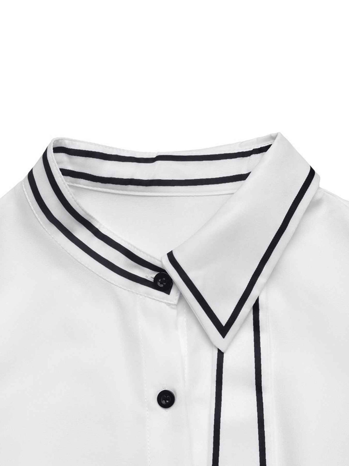 Close-up of a white collared shirt with thin black piping trim along the collar and front placket, plus black buttons.