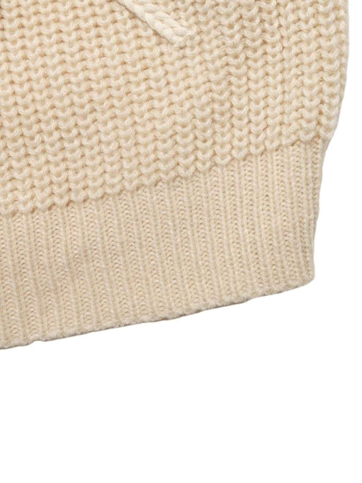 Close-up of a cream-colored chunky knit fabric with a ribbed cuff and a small matching drawstring detail, shown against a plain white background.