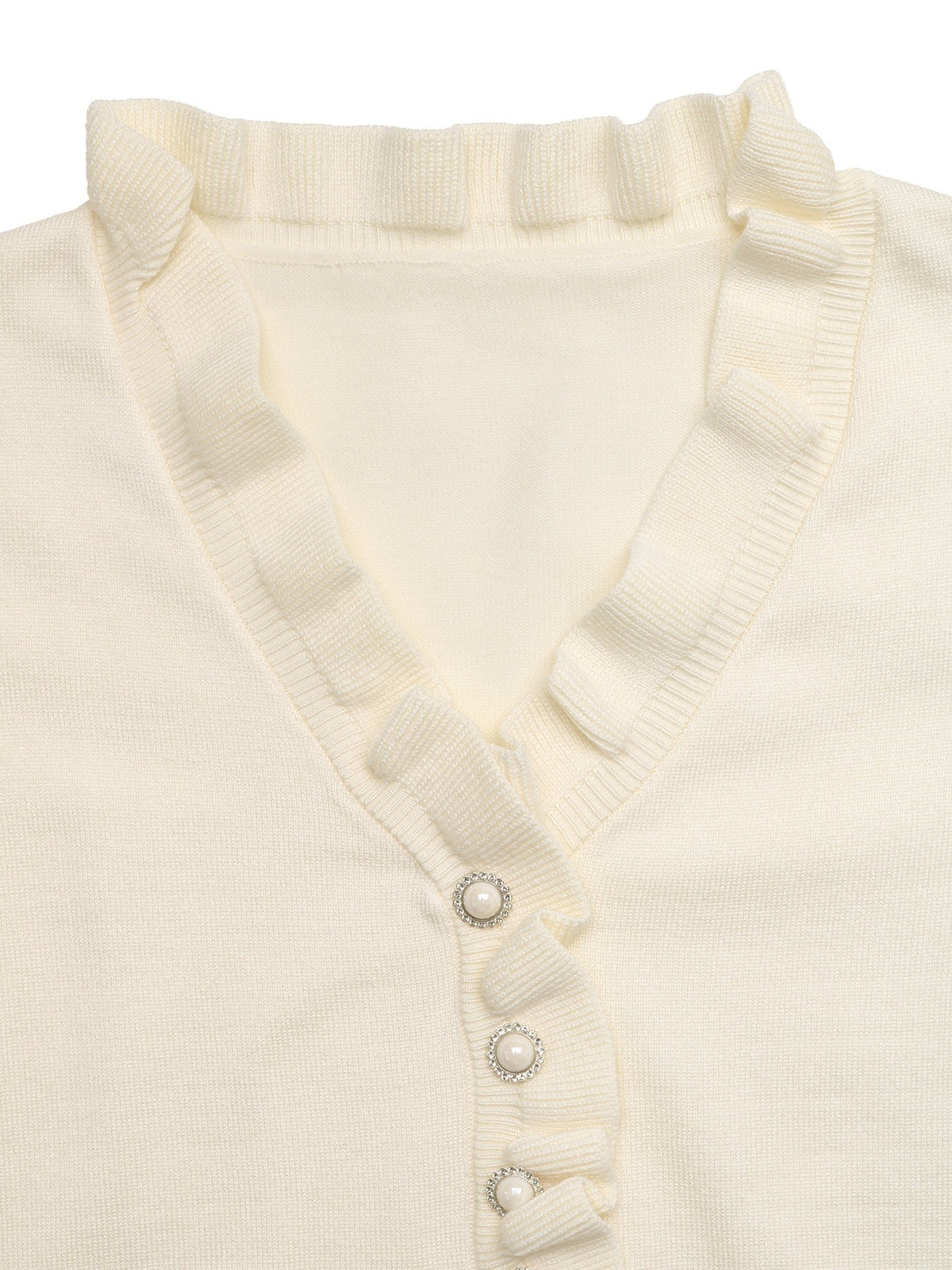 Close-up of a cream-colored ribbed knit cardigan featuring a ruffled V-neckline and decorative pearl-like buttons with silver-toned crystal accents.