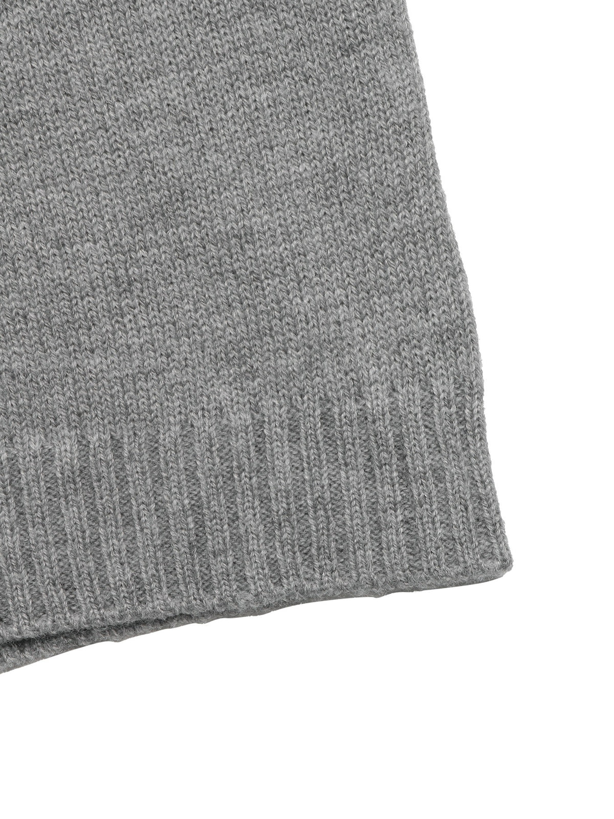 Close-up of a gray ribbed knit fabric, showing the texture and edge of a sweater or scarf on a plain white background.