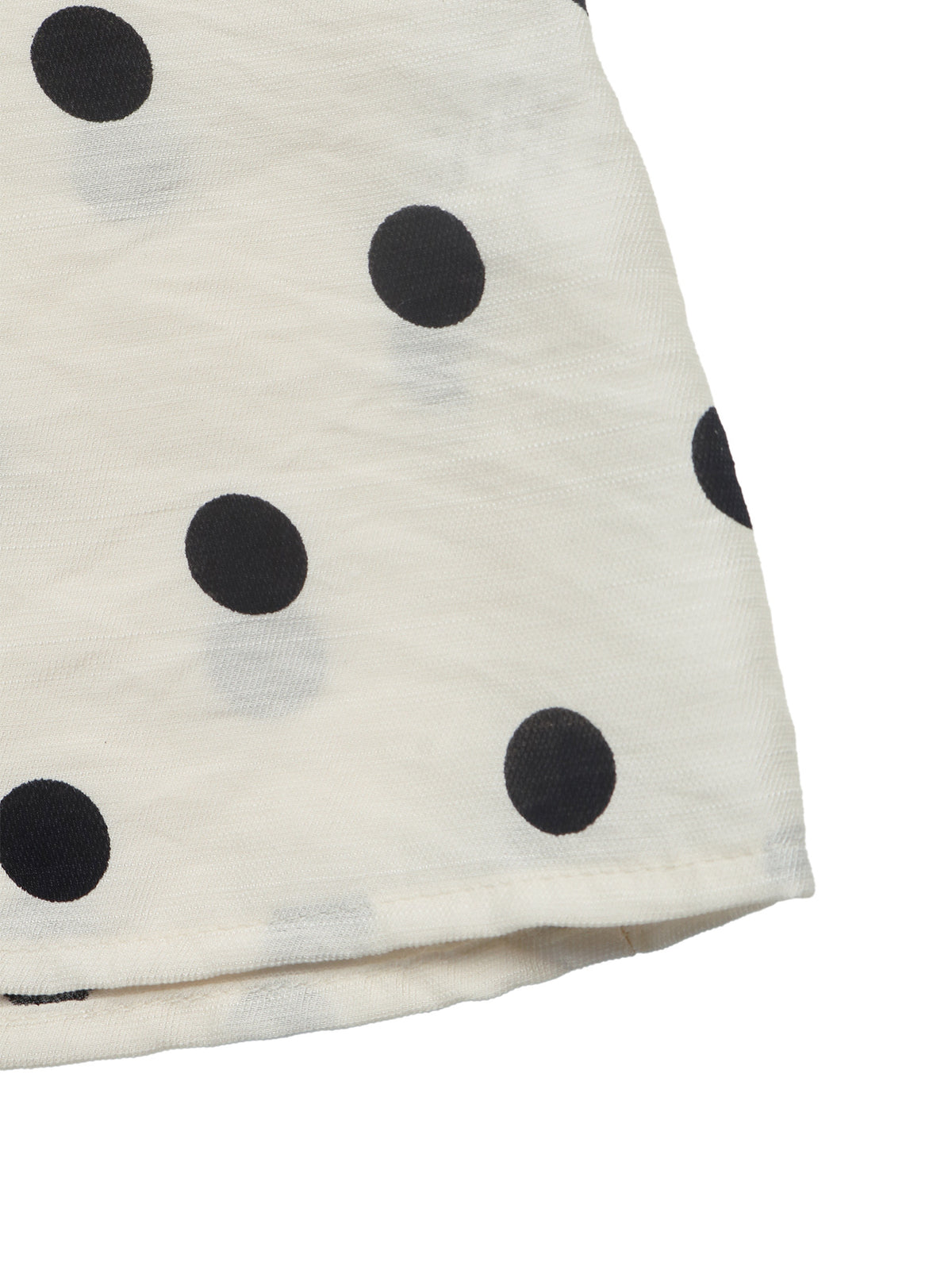 A close-up of a white or off-white fabric item, likely a scarf or bandana, featuring a black polka dot pattern on a clean white background.