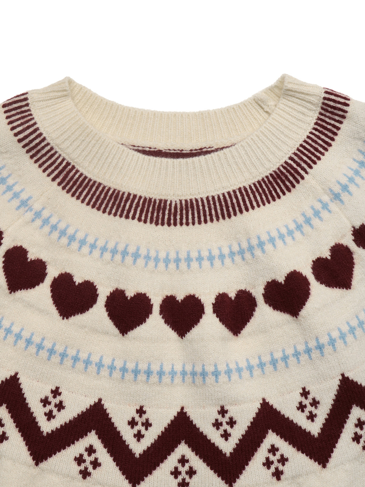 Close-up of a cream-colored knit sweater with a Fair Isle pattern featuring dark burgundy hearts, light blue stitched lines, and a matching zigzag border at the bottom.
