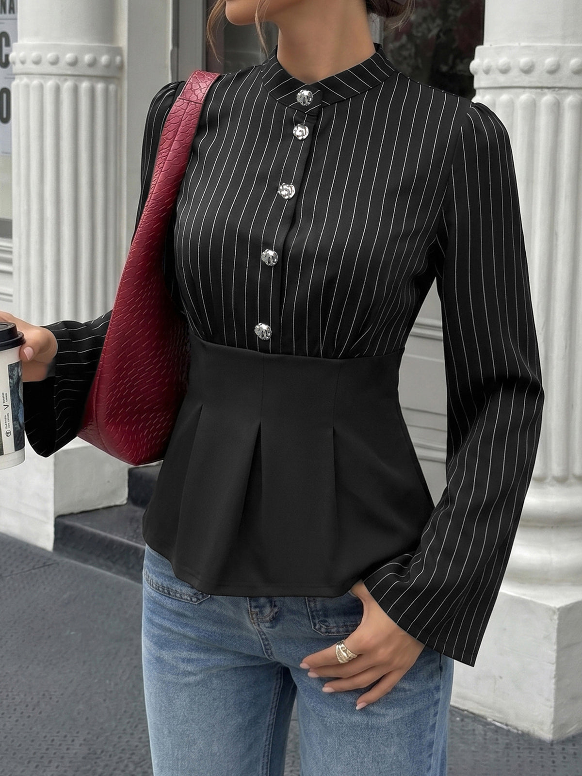 Person wearing a black pinstripe blouse with a red bag in an urban setting