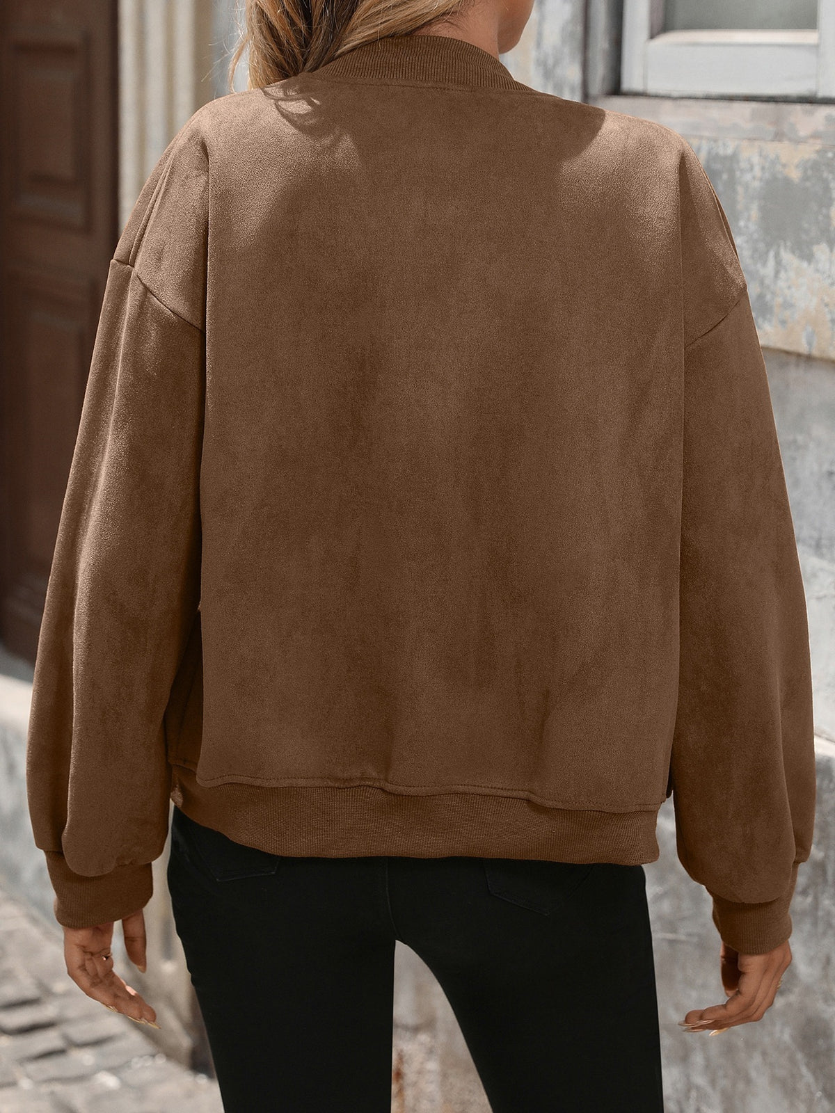 Person wearing a brown suede jacket in an urban setting