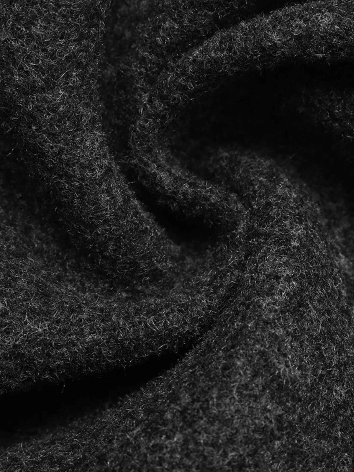 A close-up of dark charcoal gray textured fabric with soft folds and a heathered, fuzzy surface.