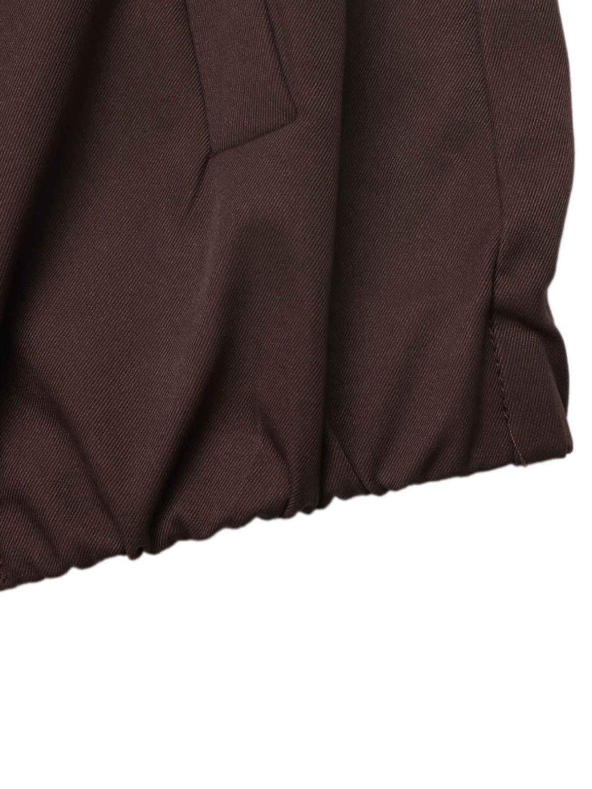 Close-up of a dark brown textured fabric garment, showing a pleated or gathered waistband and seam details against a plain white background.