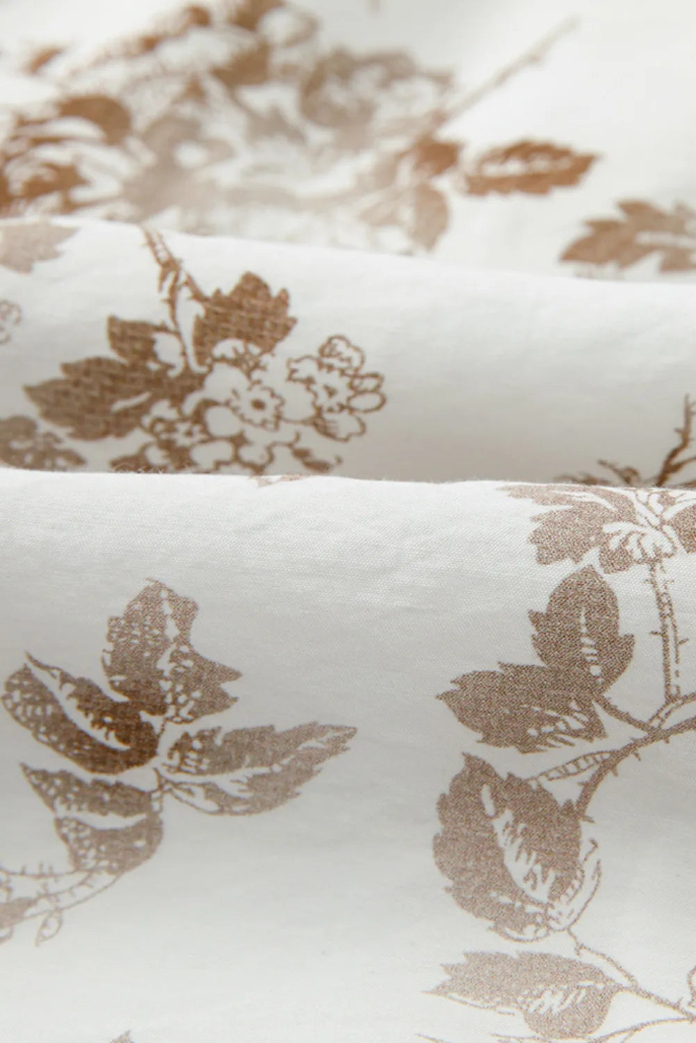Close-up of fabric with brown floral pattern on white background