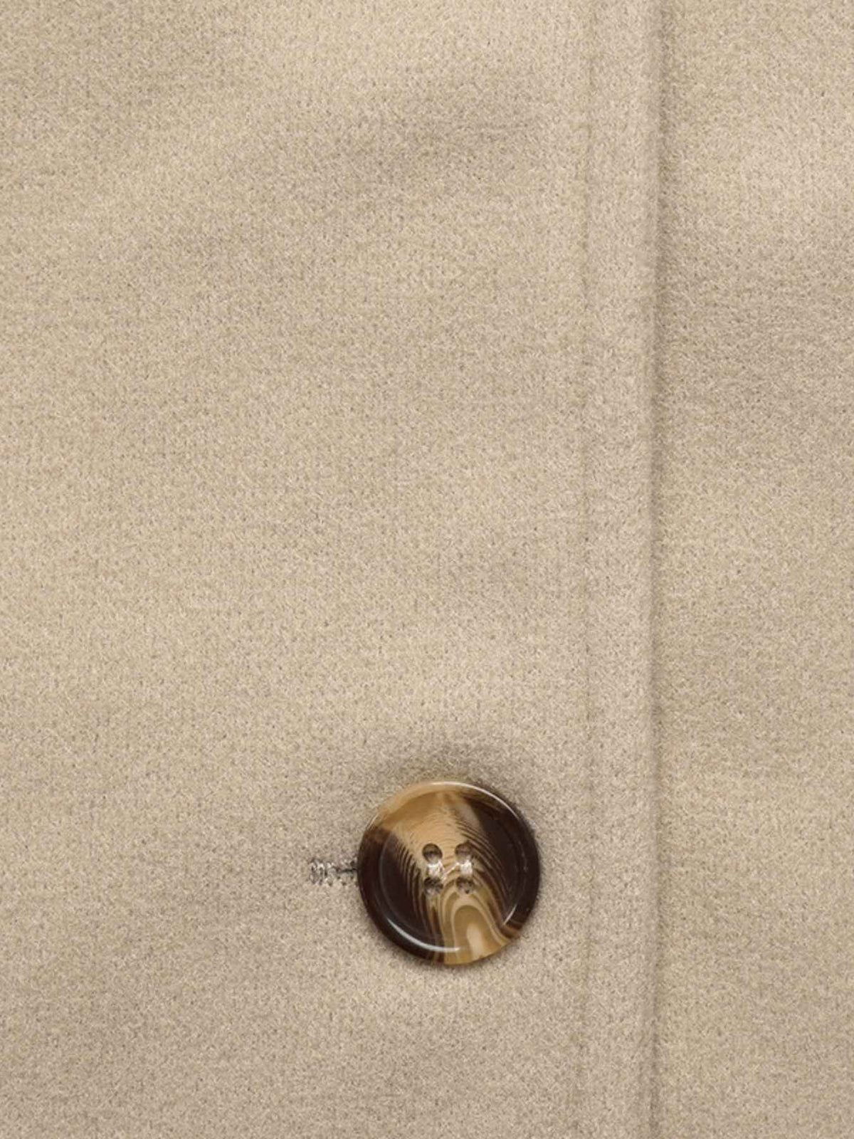 Close-up of a beige textured fabric surface with a single round brown and gold marbled button near the lower center.