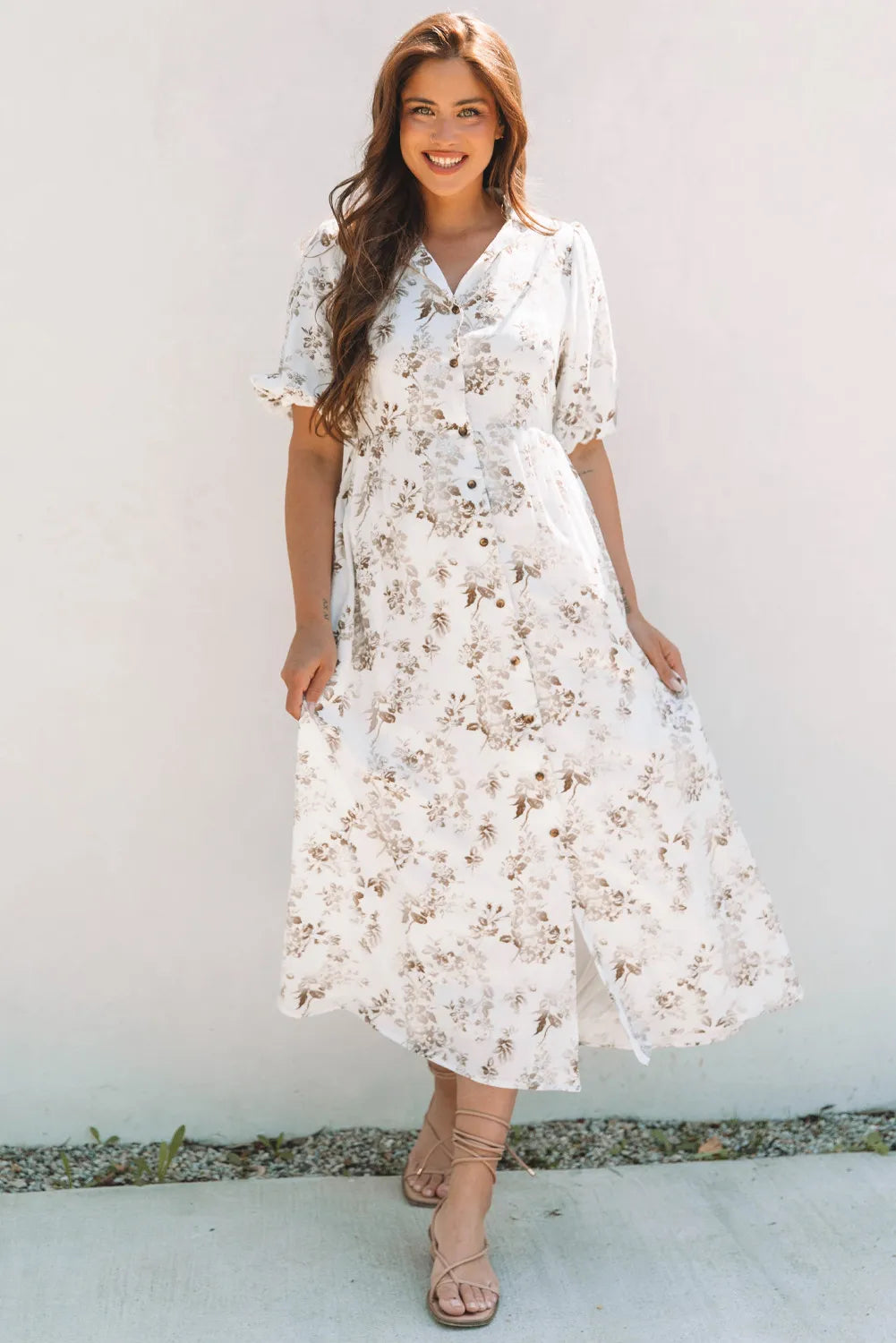 Woman wearing a white floral dress against a plain background
