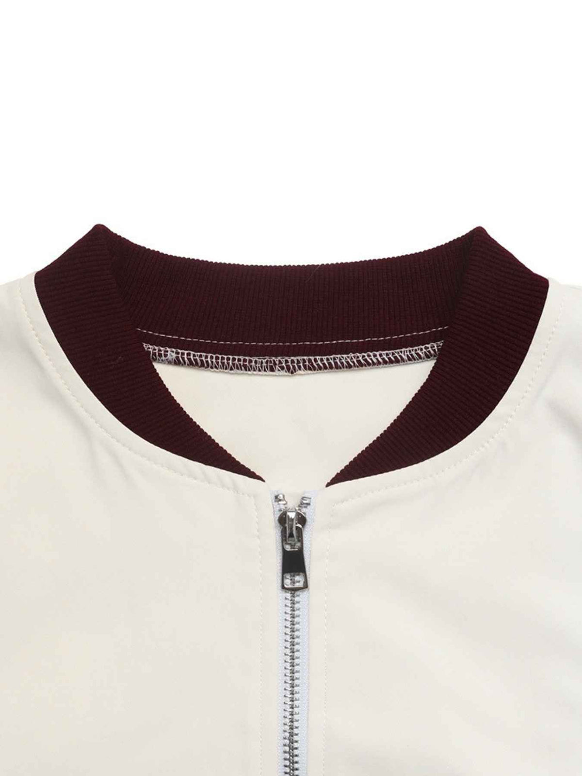 Close-up of a baseball-style jacket collar with a dark burgundy ribbed knit trim and a silver zipper on an off-white body, shown against a plain white background.