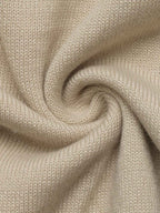 A close-up of a soft knit fabric in a warm light beige or oatmeal tone, arranged in a spiral drape to show texture and flexibility.