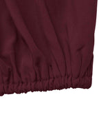 Close-up of a dark burgundy fabric garment with an elasticized gathered hem, shown against a plain white background.