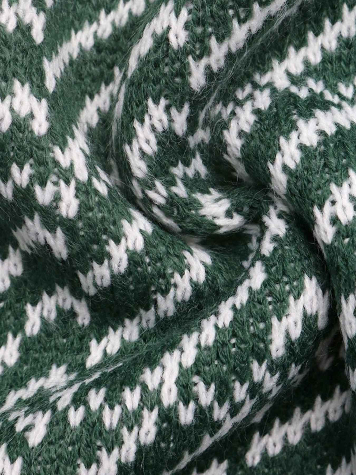 A close-up of a knitted fabric with a dark green and white pattern, shown in a twisted fold to highlight the texture and weave.