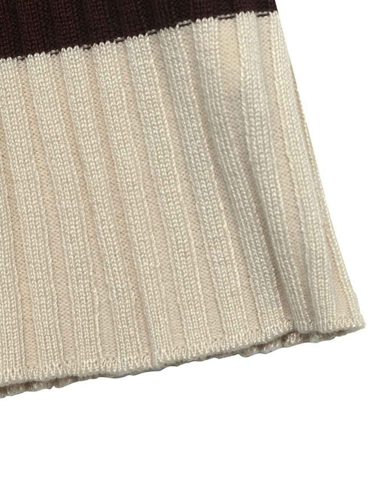Close-up of a ribbed knit textile, likely a sweater or scarf, showing a warm cream-beige body with a dark brown band at the top edge on a white background.