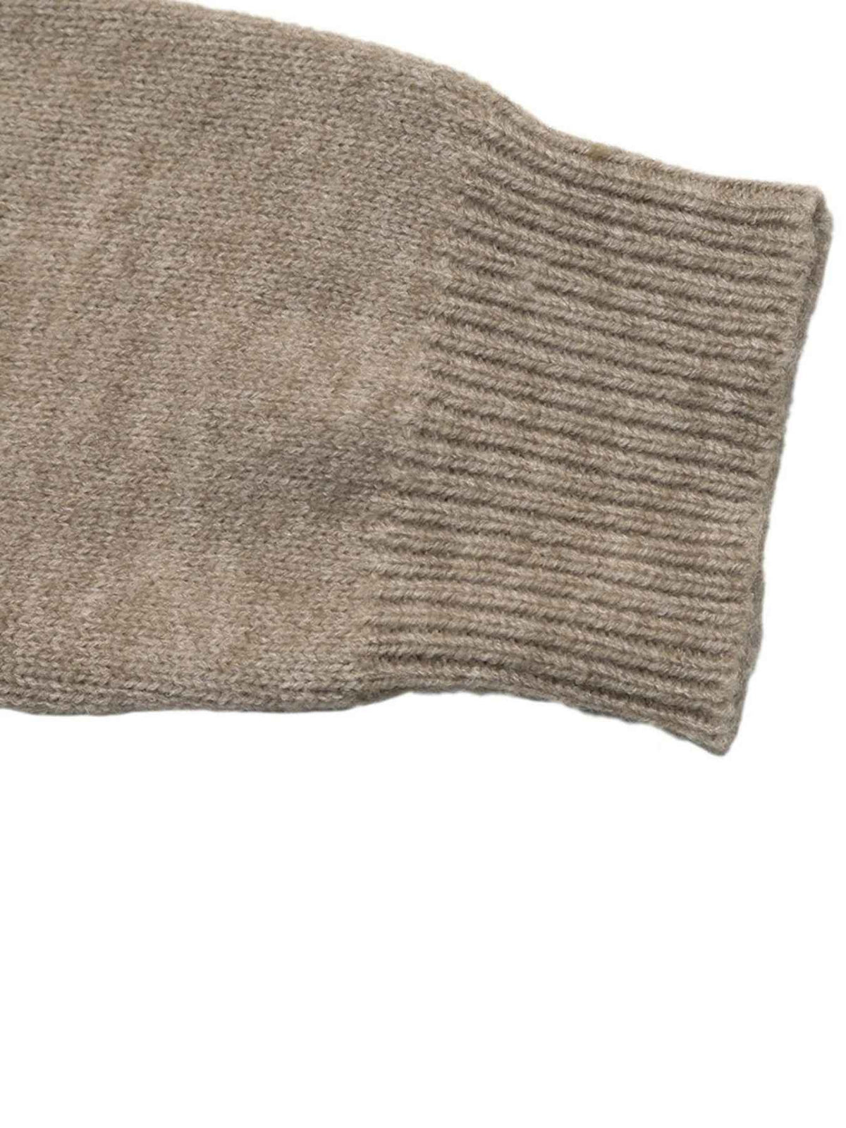 Close-up of a ribbed knit sweater sleeve cuff in a warm taupe-beige color, showing the texture and construction against a plain white background.