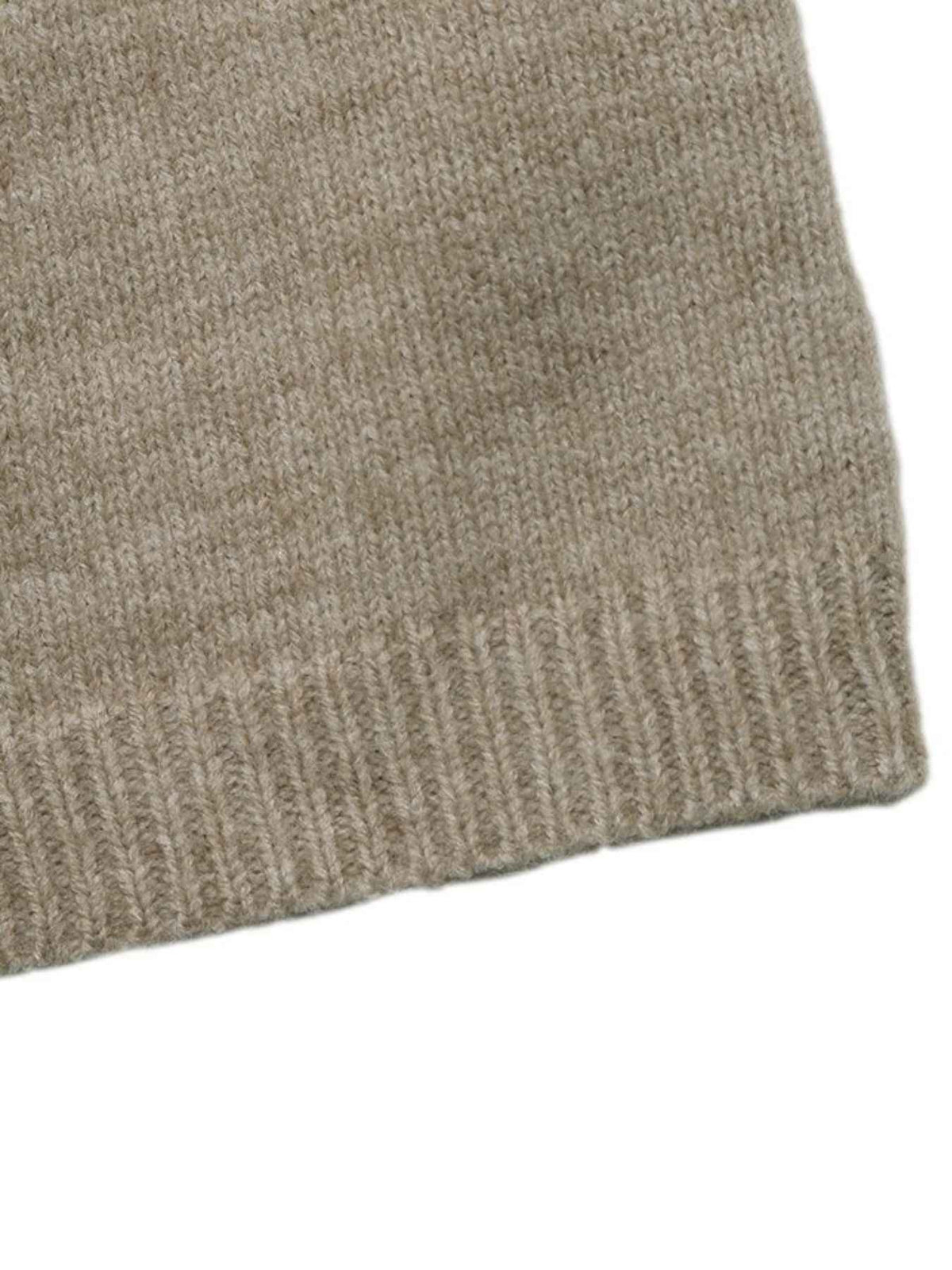 Close-up of a ribbed knit fabric in a warm taupe-beige color, showing the texture and edge of the material against a white background.