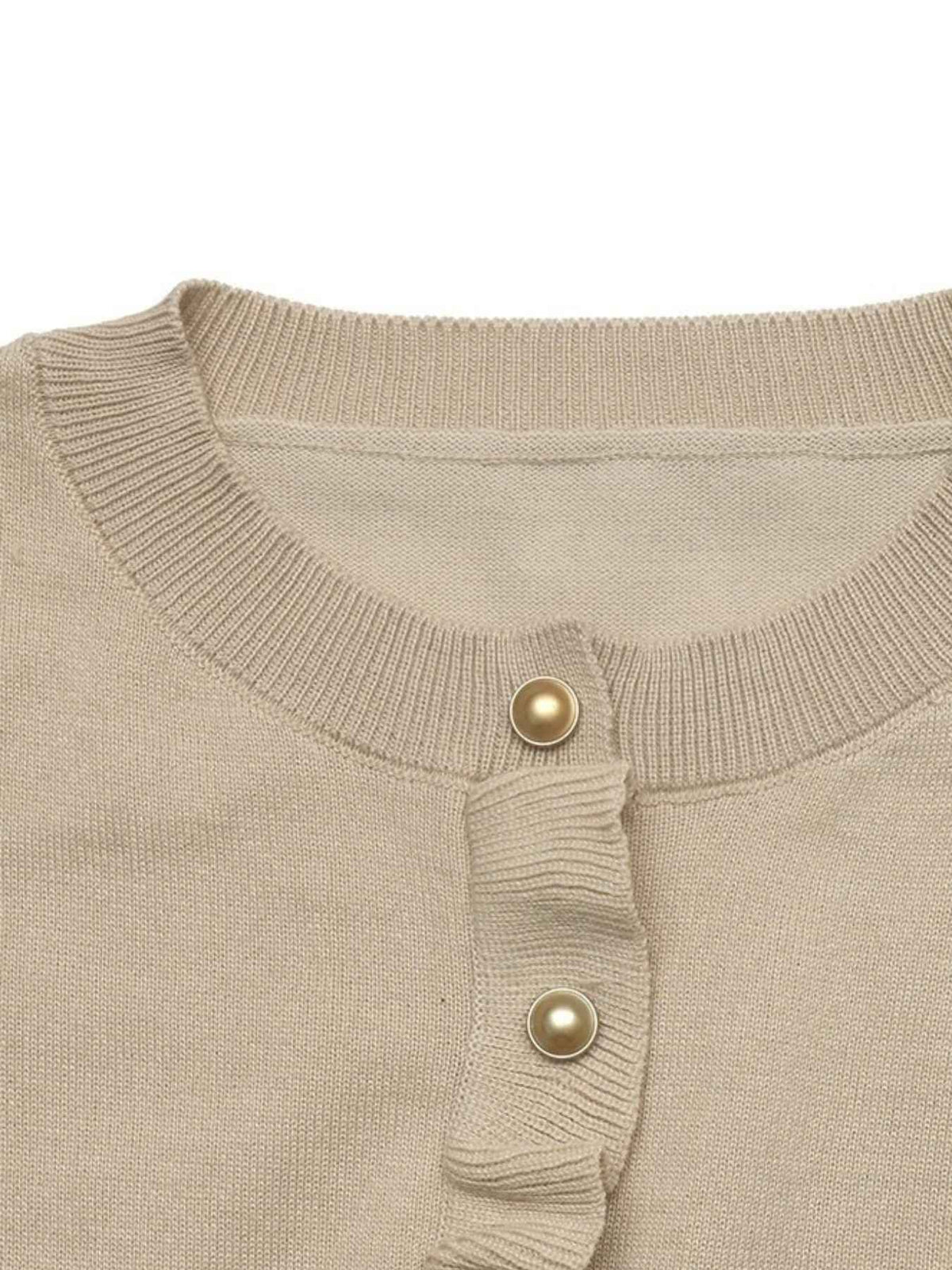 Close-up of a beige ribbed knit top with a ruffled placket and two gold-tone decorative buttons, shown against a plain white background.