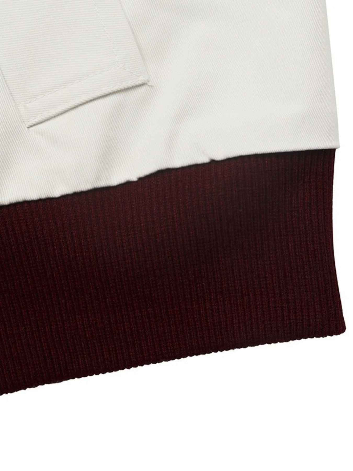 Close-up detail of a garment showing a white fabric section above a dark burgundy ribbed knit hem on a white background.