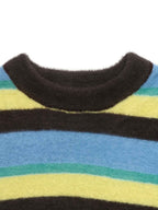 Close-up of a fuzzy striped knit sweater with a dark brown ribbed crew neck, featuring horizontal stripes of blue, yellow, teal, and dark brown on a white background.