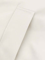 Close-up of a light cream or off-white fabric surface with a folded corner showing the texture and stitching.