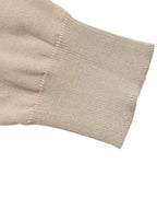 Close-up of a beige knit sleeve cuff showing the ribbed texture and stitching on a plain white background.