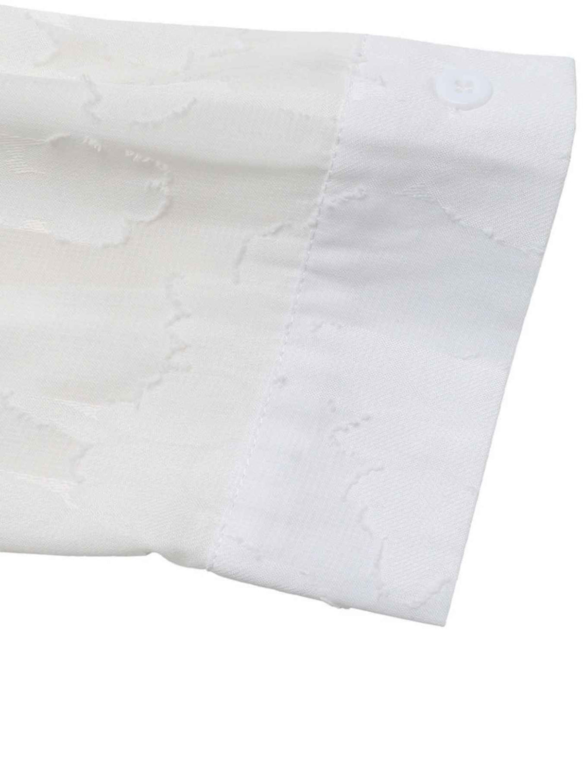 Close-up of a white fabric product showing a textured jacquard pattern and a buttoned cuff detail.