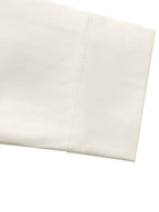 A close-up of a folded off-white or cream fabric with a clean stitched edge, shown against a plain white background.