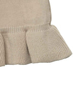 Close-up of a ribbed knit garment in a light warm beige or oatmeal color, showing the texture and ruffled hem detail against a plain white background.
