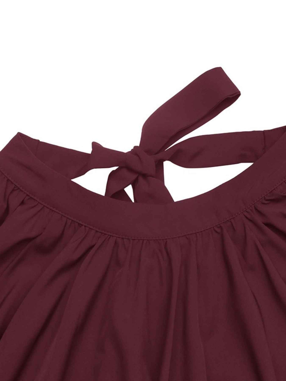 Close-up of a dark burgundy top with a tie-back neckline, showing the fabric texture and gathered waist details against a white background.