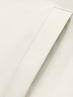 Close-up of a light cream or off-white fabric surface with a folded panel and visible stitching.