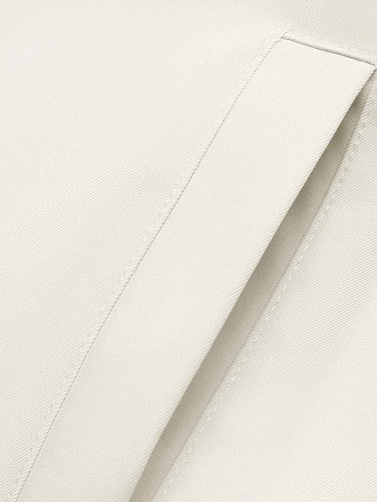 Close-up of a light cream or off-white fabric surface with a folded panel and visible stitching.