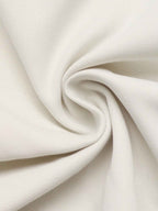 A close-up of off-white fabric with a subtle ribbed texture, artistically swirled and draped to show its soft folds and texture.