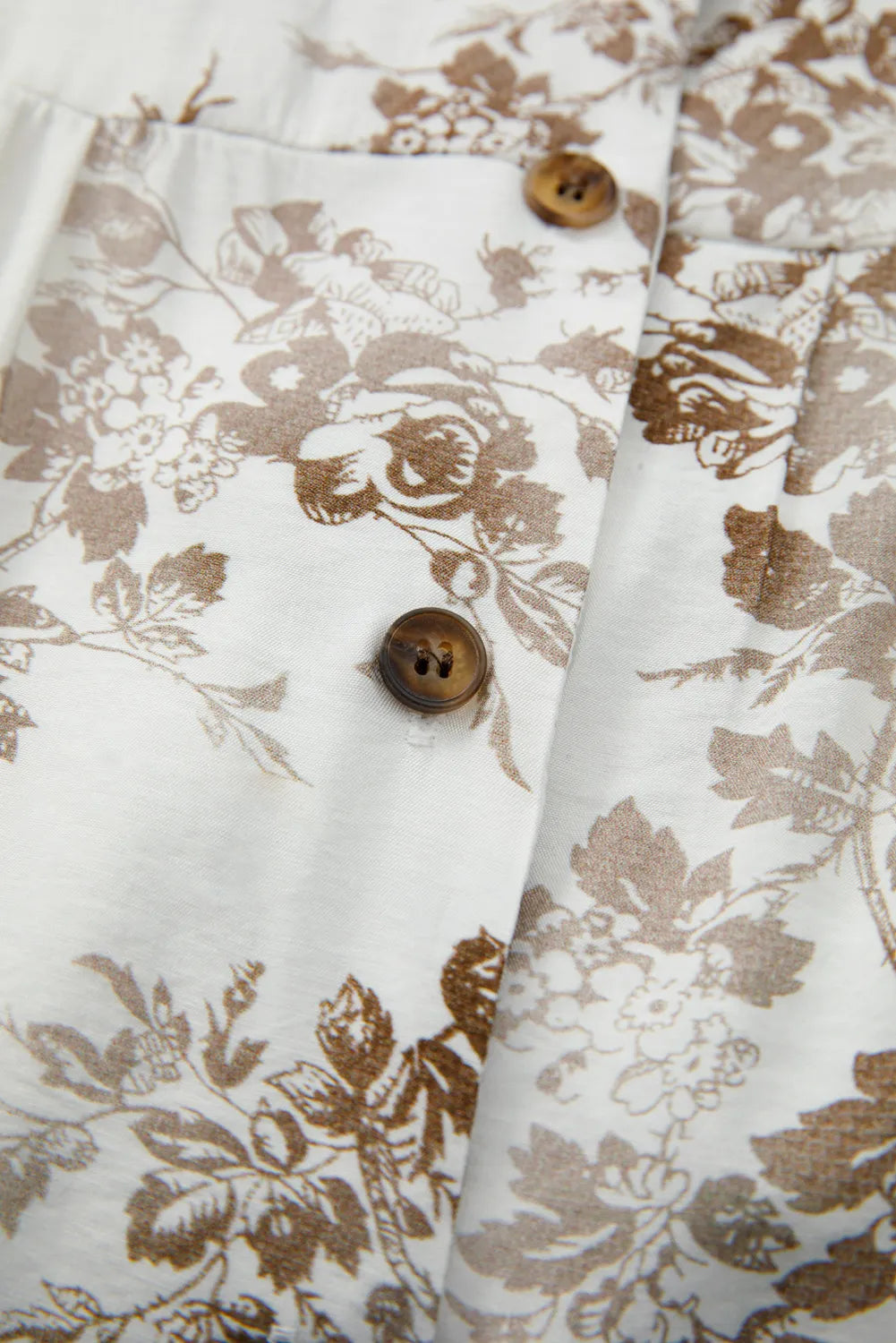 Close-up of a floral-patterned fabric with brown buttons on a white background