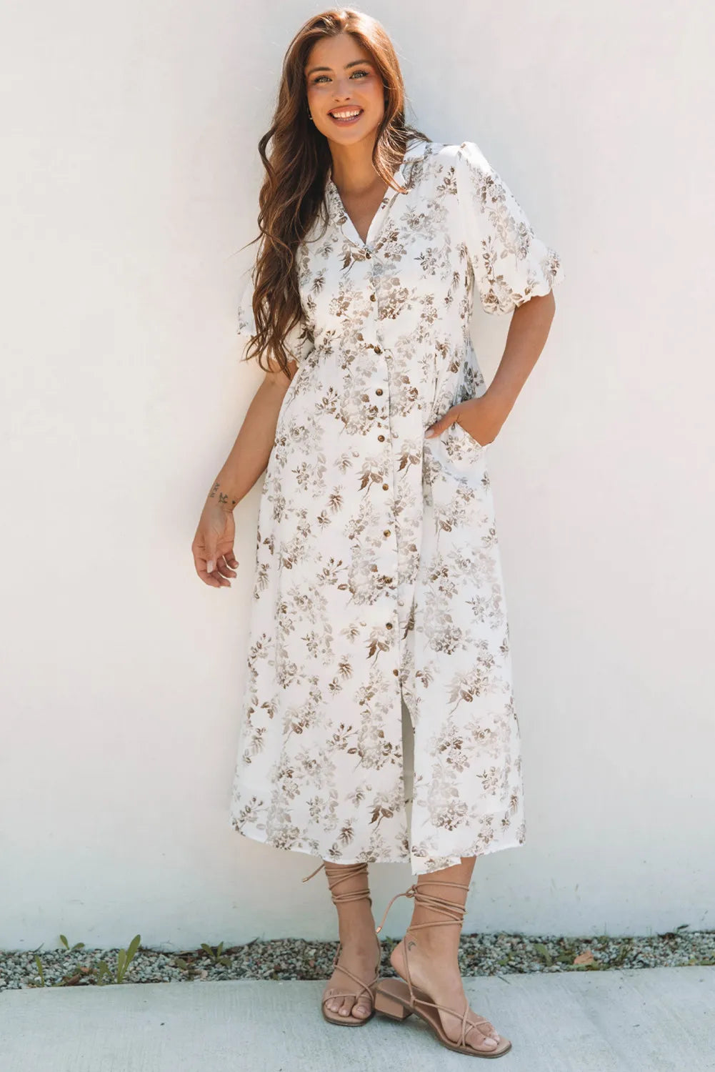 Woman wearing a floral dress against a white wall