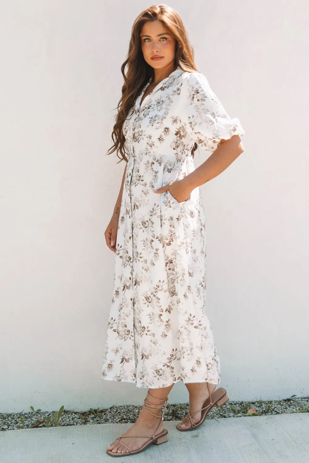 Woman wearing a white floral dress against a plain background