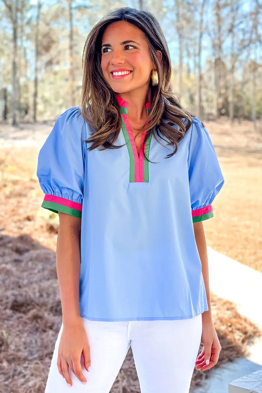 Woman wearing a light blue blouse with colorful trim outdoors