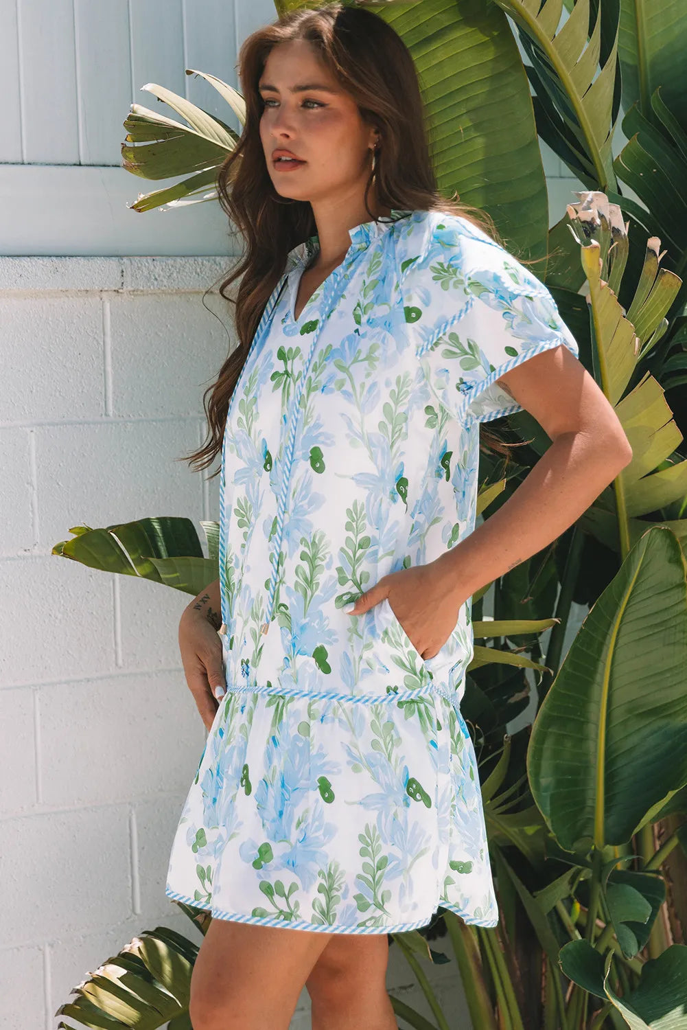 Woman wearing a floral dress standing in front of tropical plants.