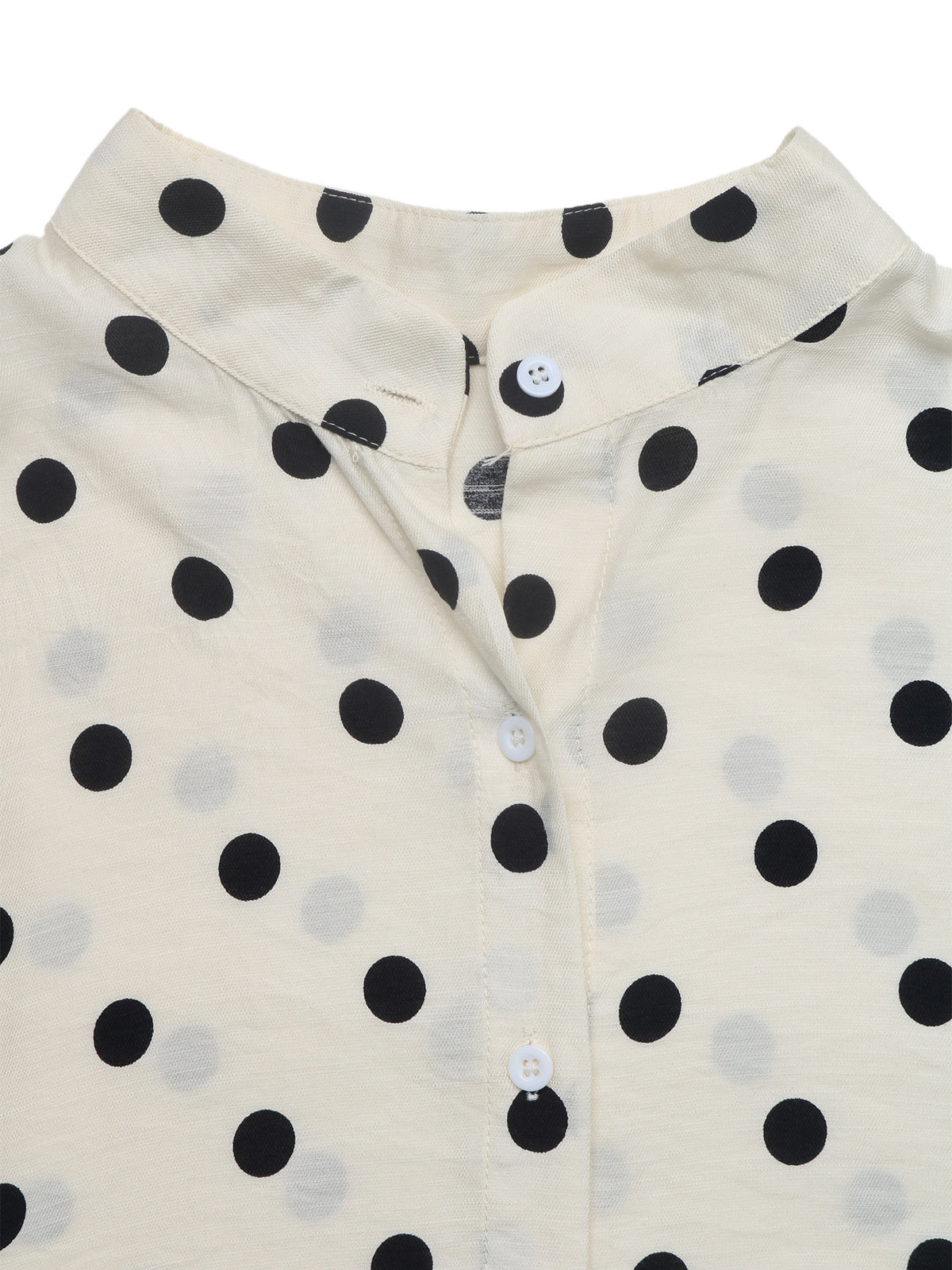 Close-up of a cream-colored button-up shirt with a black polka dot pattern, featuring a pointed collar and white buttons.