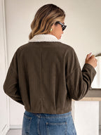 A woman viewed from behind wearing an olive brown corduroy cropped jacket with a white sherpa collar, paired with blue jeans.