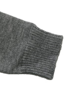 Close-up of a dark gray ribbed knit sleeve cuff on a plain white background.