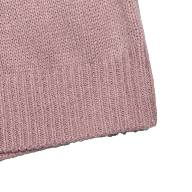 Close-up of a dusty pink ribbed knit fabric, showing the detailed knit texture and folded hem on a white background.