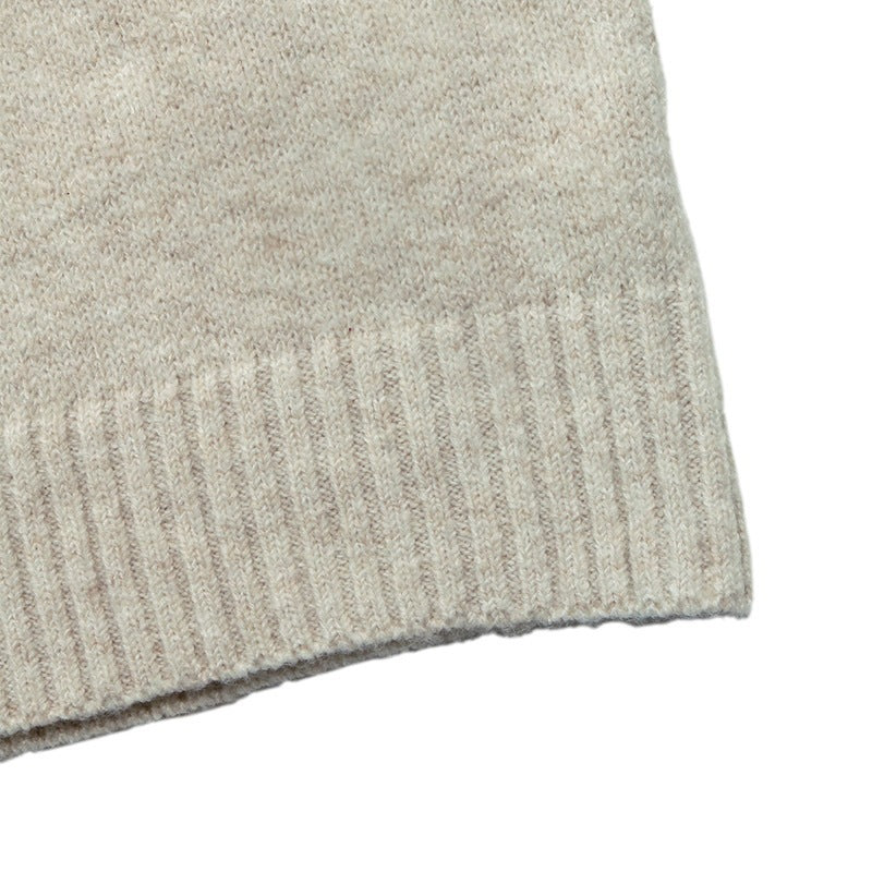 Close-up of a knit fabric cuff in a light oatmeal beige color, showing the ribbed knit texture against a plain white background.