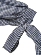 Close-up of a navy blue and white checkered fabric garment tied in a knot, showing the texture and pattern against a white background.
