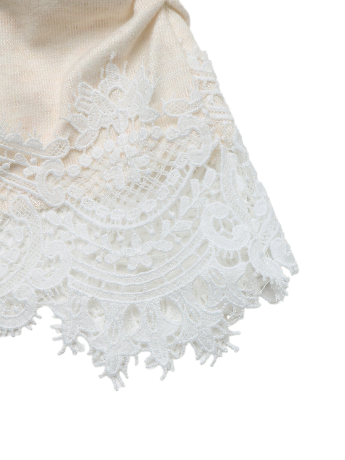 Close-up of a cream-colored knit fabric with an intricate white lace trim along the edge, set against a plain white background.