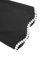 Close-up of a black fabric item with a decorative white scalloped edge trim on a white background.