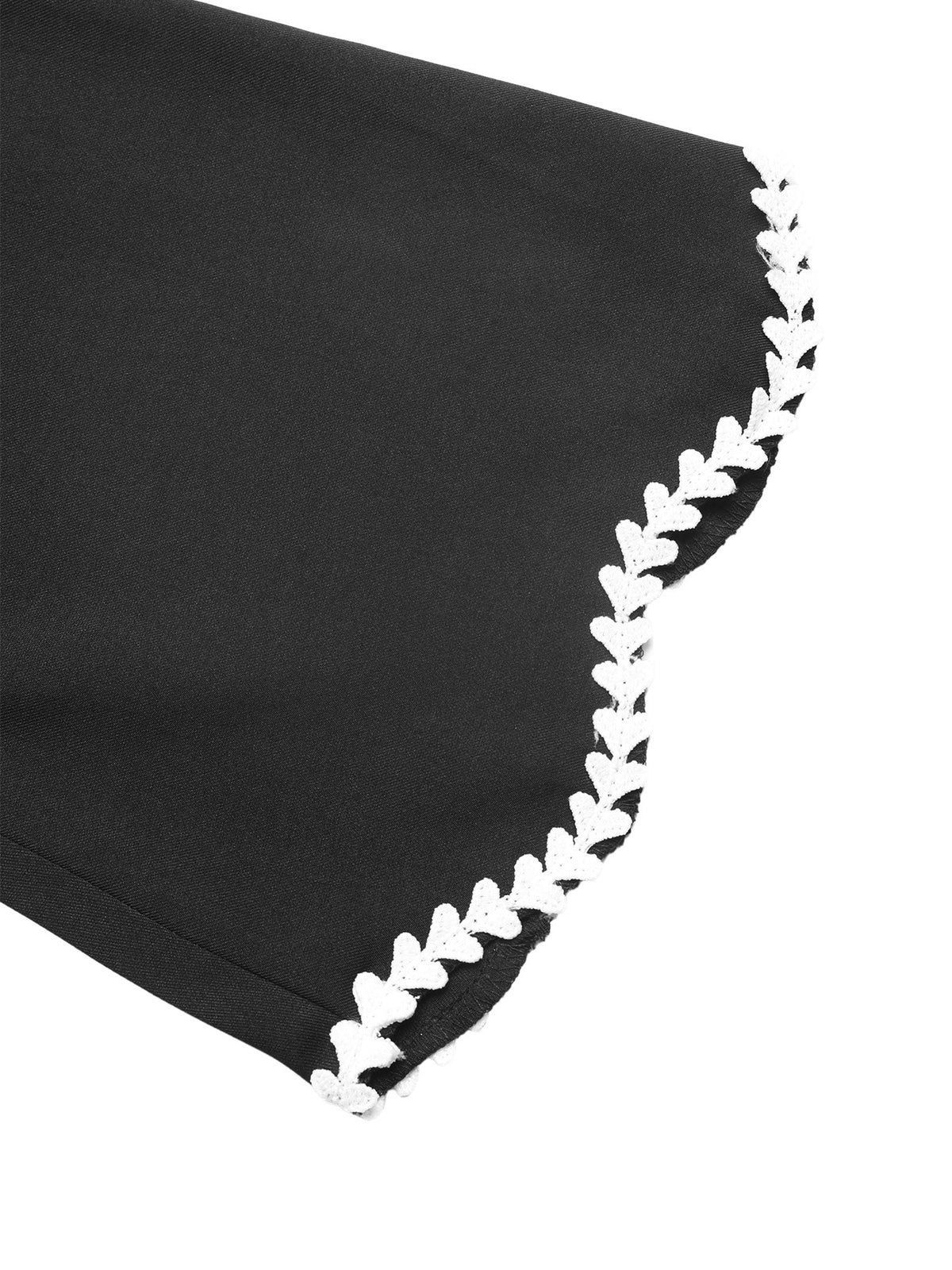 Close-up of a black fabric item with a decorative white scalloped edge trim on a white background.