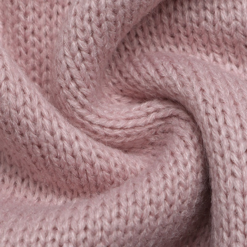 A close-up of a soft, dusty pink knitted fabric with a textured ribbed pattern, arranged in a gentle swirl.