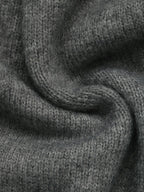 Close-up of a dark gray knitted fabric with a soft, textured weave and draped folds.
