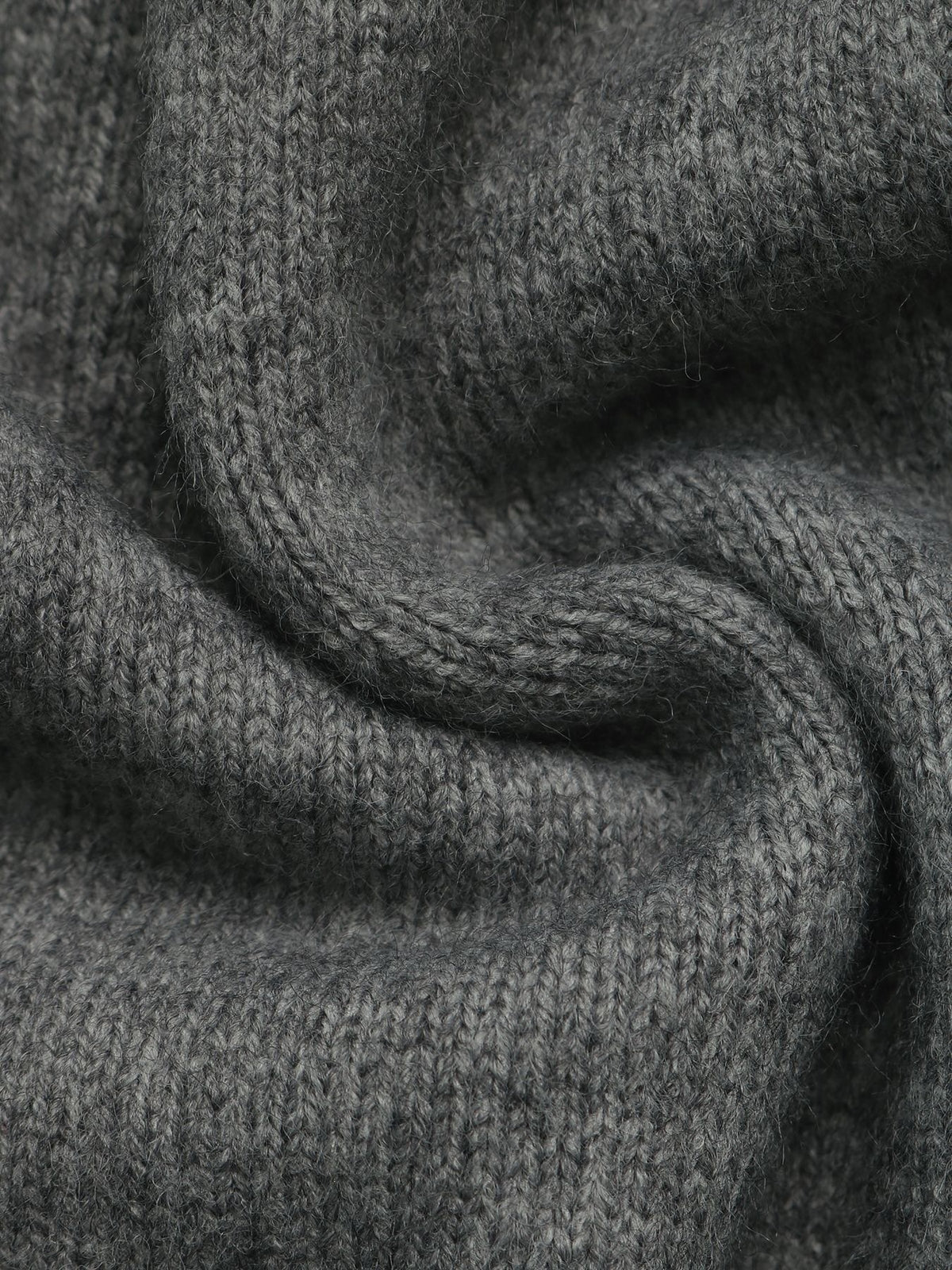 Close-up of a dark gray knitted fabric with a soft, textured weave and draped folds.