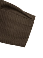 A close-up of a dark brown ribbed knit fabric, showing the texture and folded edge, set against a plain white background.